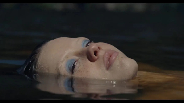 a woman with blue eyeshadow's face sticking out of water