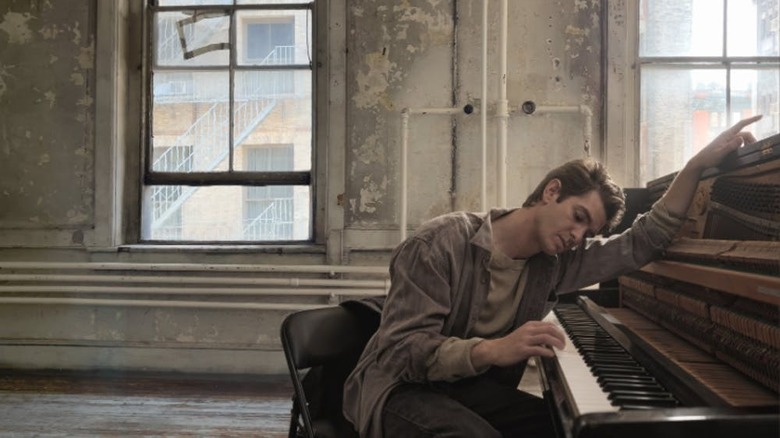 Andre Garfield draped over a piano in Tick, Tick...BOOM!