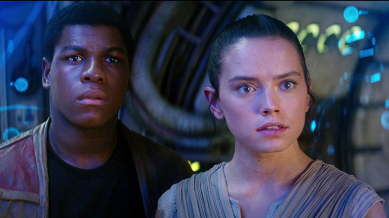 John Boyega's Finn and Daisy Ridley's Rey standing on the Millennium Falcon in Star Wars: The Force Awakens