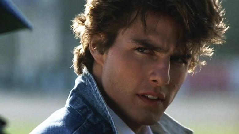 Cole Trickle wearing a jean jacket and giving a piercing look in Days of Thunder