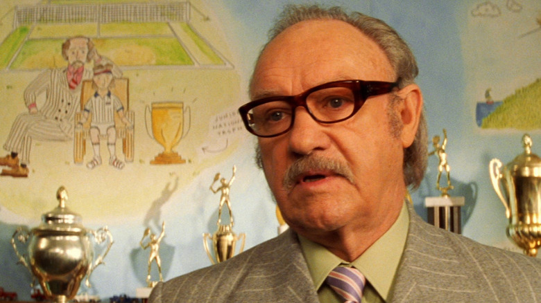 Gene Hackman as Royal Tenenbaum in front of trophies