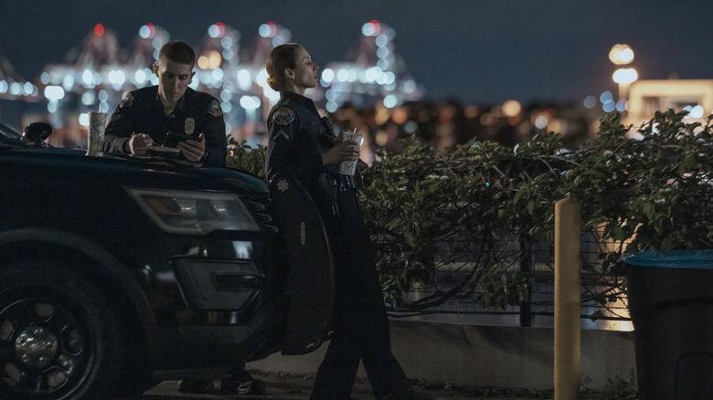 Troian Bellisario's Traci Harmon and Brandon Larracuente's Alex Diaz leaning on a police car in On Call