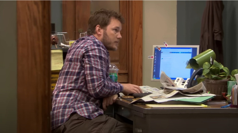 Andy Dwyer sitting at desk in Parks and Recreation