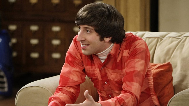 Howard in a red plaid shirt sitting on a couch and leaning forward on The Big Bang Theory