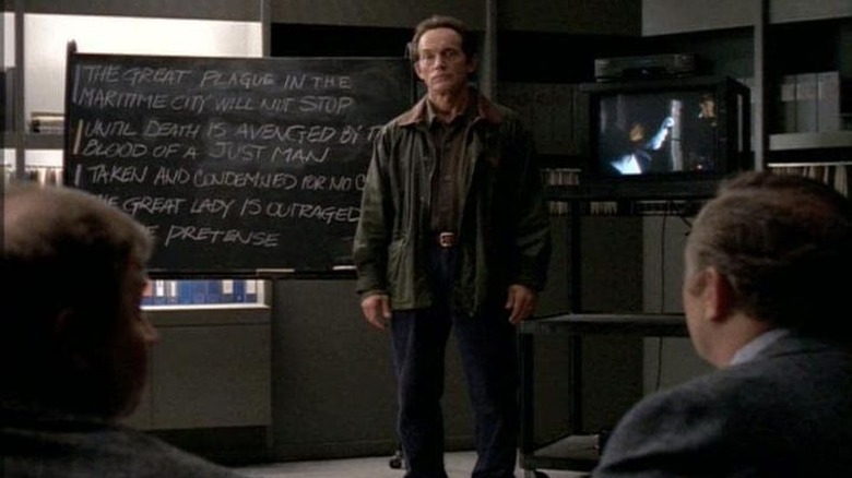 Lance Henriksen in front of chalkboard Millennium