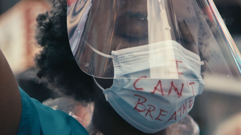 A young woman wears a mask with "I Can't Breathe" written on it.