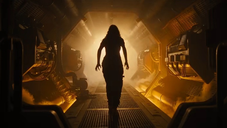 A woman walking down an orange spaceship hallway