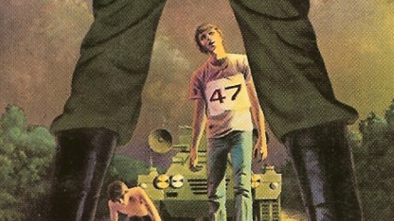 From between someone's legs, a teenager wearing "47" walks in front of a tank, from The Long Walk book cover