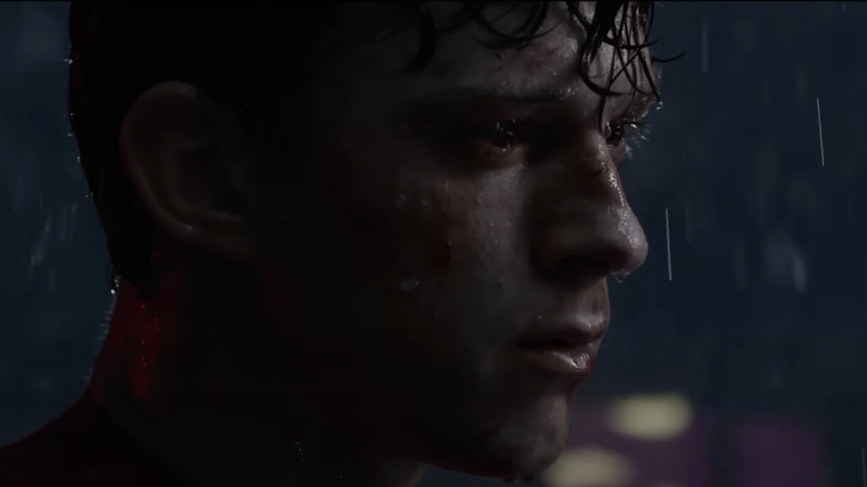 Tom Holland's Peter Parker/Spider-Man looks beaten down as he looks off into the distance in a rain storm Spider-Man: No Way Home