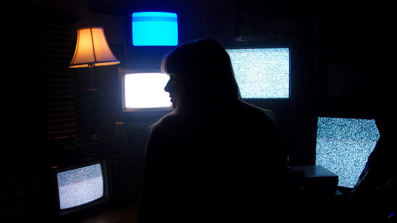 Woman in front of TVs with static