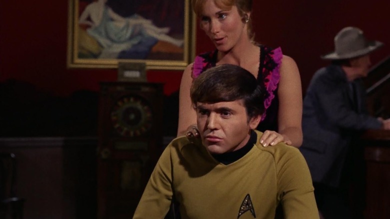 Ensign Chekov in a minimalist version of an Old West saloon, being massaged by an alehouse girl on Star Trek