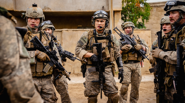 Charles Melton, like a soldier named Jake, leads a squad of armed troops in the Iraqi streets in the war