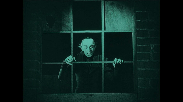 Max Schreck as Count Orlok standing behind a window frame in Nosferatu: A Symphony of Horror