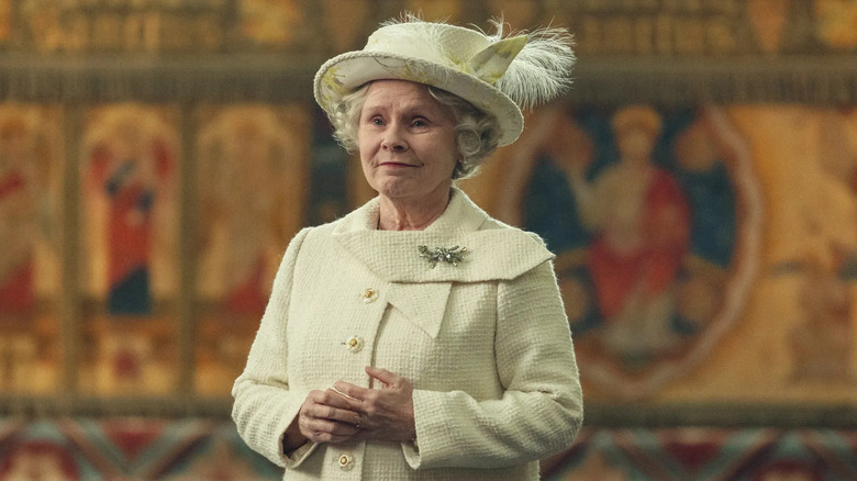 Queen Elizabeth II clasping her hands and smiling on The Crown