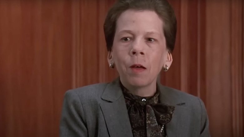 Linda Hunt as Miss Schlowski stands next to a wall in Kindergarten Cop