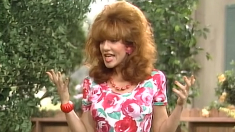 Katey Sagal as Peggy Bundy, shrugging in the yard on Married with Children