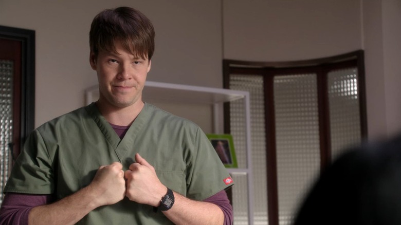 Morgan (Ike Barinholtz) in his green scrubs, clutching his hands to his chest, on The Mindy Project