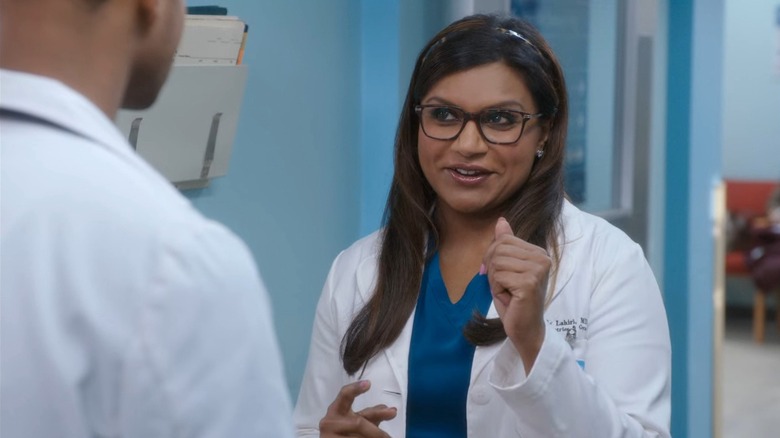 Dr. Mindy Lahiri (Mindy Kaling) wearing her lab coat and glasses, smiling, on The Mindy Project