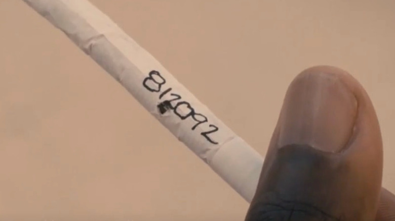 Xavier holds a cigarette with numbers on it in Paradise