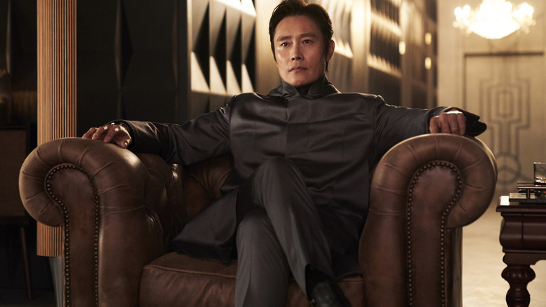 Lee Byung-hun as Front Man sitting villainously on an armchair in Squid Game season 2