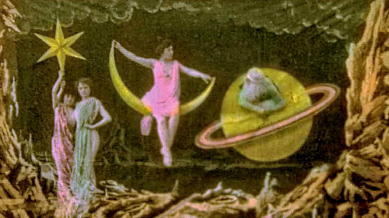 A pair of women holding a star, a woman sitting on a crescent moon, and another sitting on the planet Saturn from A Trip to the Moon