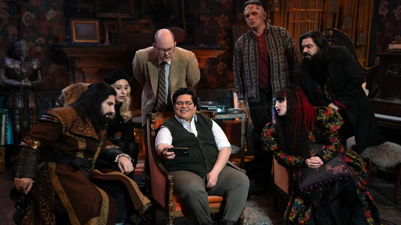 Nandor, The Guide, Colin Robinson, the Monster, Laszlo, and Nadja all lean in to watch Guillermo's phone in What We Do in the Shadows