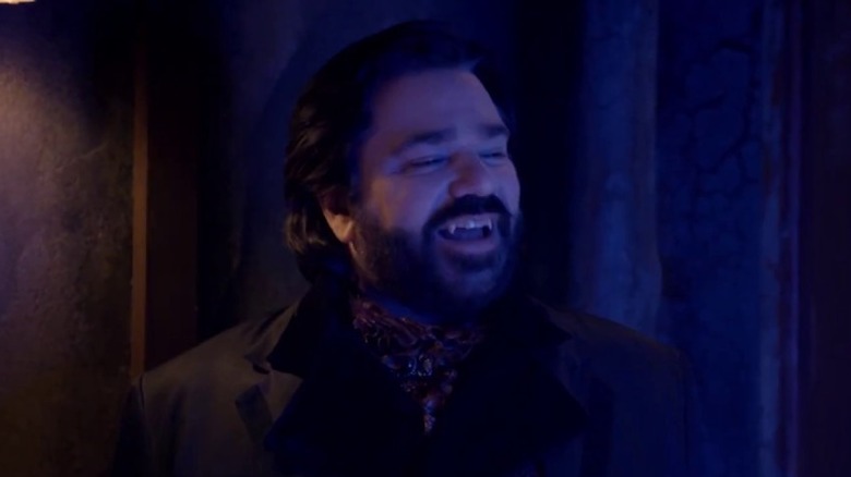 Matt Berry as Lazlo Cranvensworth smiling with open vampire fangs in What We Do in the Shadows