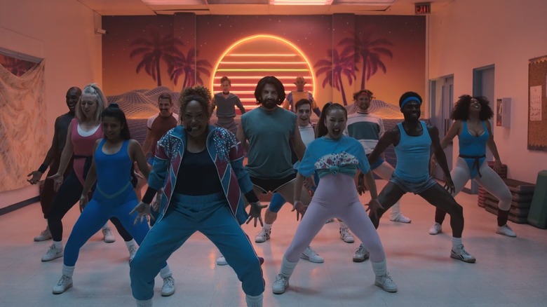 Cree Summer and Kayvan Novak perfoming dancing yoga in a group in What We Do in the Shadows