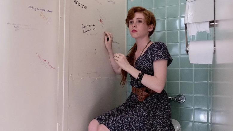 Beverly sits in a bathroom stall