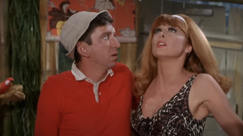 Bob Denver's Gilligan stands close to Tina Louise's Ginger Grant as she looks up at the roof of their hut in Gilligan's Island