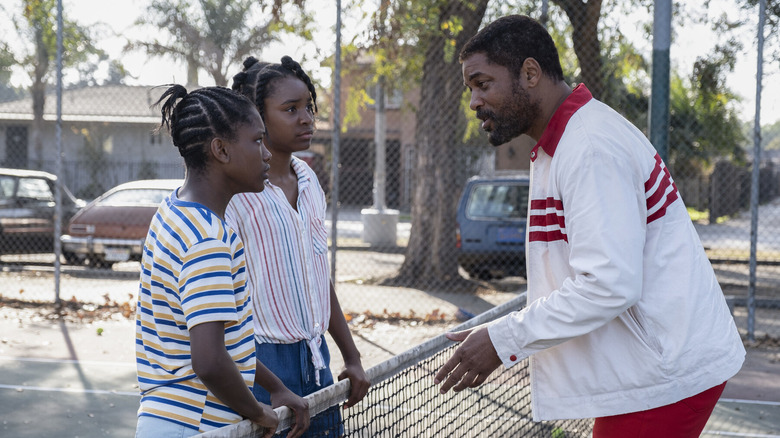 a man and two girls talking over a tennis net