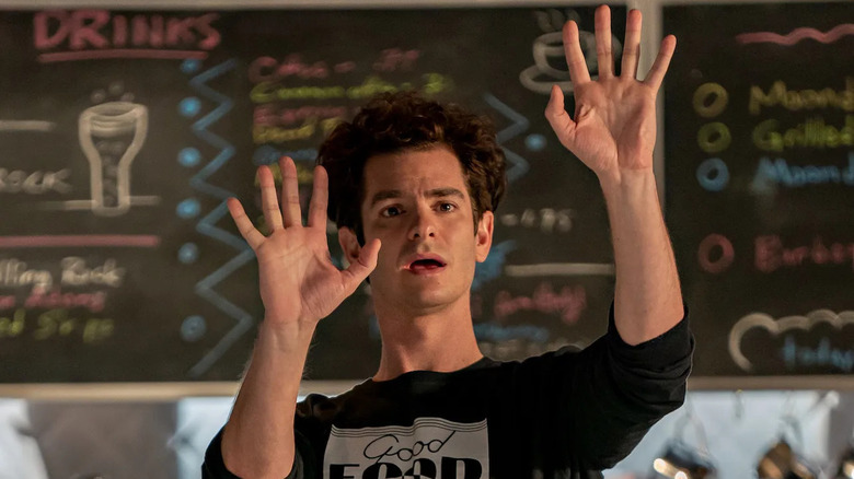 a man with both hands up in front of a chalkboard