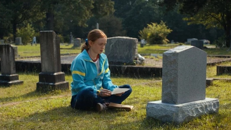 Sadie Sink's Max sits cross-legged in front of a grave in Stranger Things