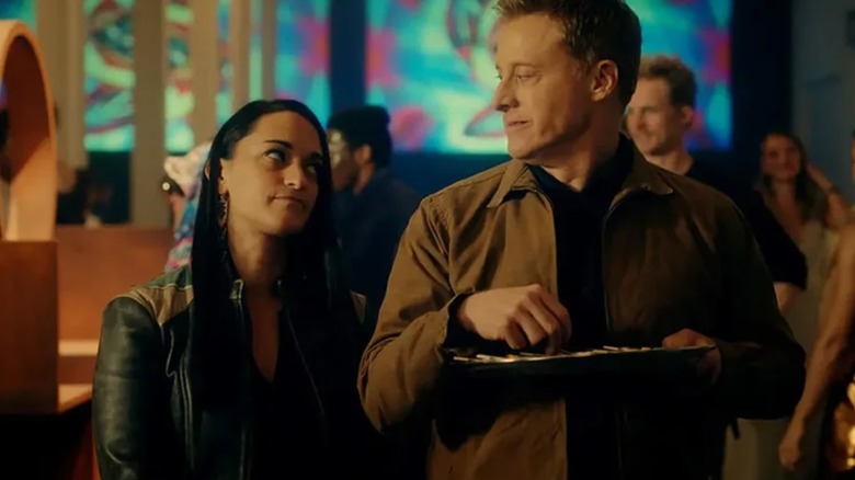 Sara Tomko's Asta and Alan Tudyk's Harry share a look while he holds a food tray in Resident Alien