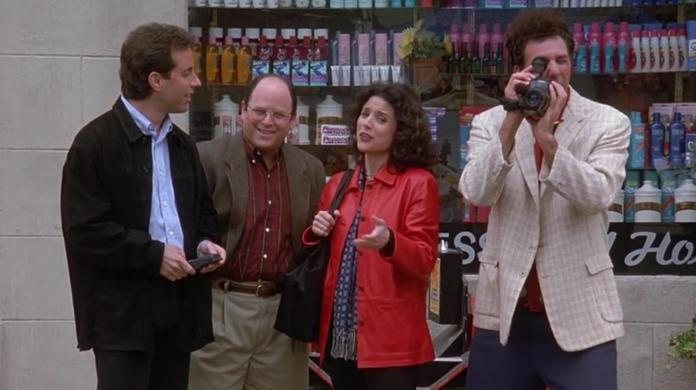 Jerry Seinfeld's Jerry, Jason Alexander's George, Julia Louis-Dreyfus' Elaine, and Michael Richards' Kramer look across the street, Kramer with a camera, in Seinfeld