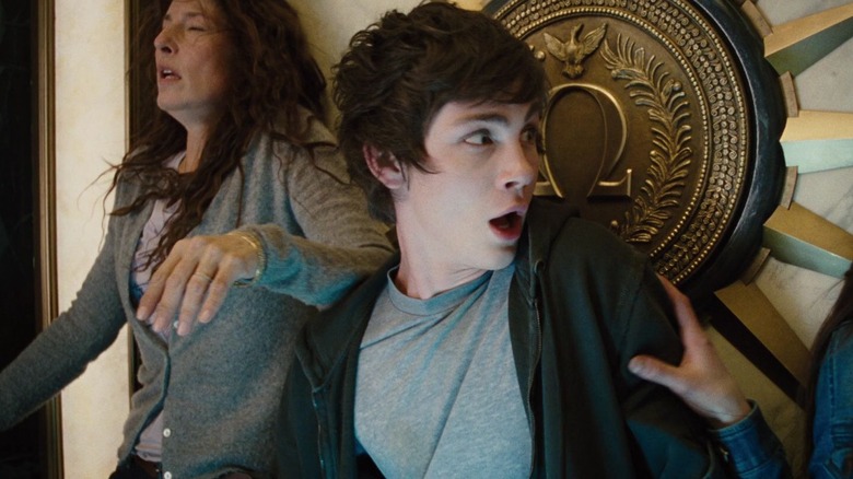 Percy Jackson and his mother, being forcibly pushed against a wall by an unseen force. A large Omega is on the wall behind them.