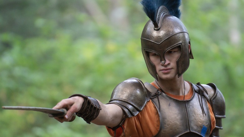 Charlie Bushnell's Luke, in Greco-Roman armor, holds out a blade in Percy Jackson and the Olympians