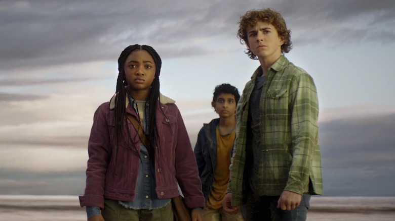 Leah Jeffries' Annabeth, Aryan Simhadri's Grover, and Walker Scobell's Percy stare with concern while standing near the ocean in Percy Jackson and the Olympians