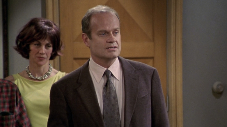 Frasier stands in his apartment with Ronee watching from behind