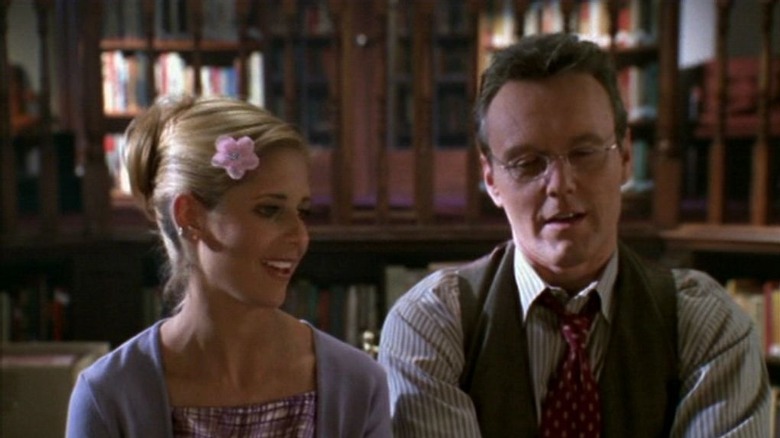 Buffy and Giles sitting next to each other in the library and smiling