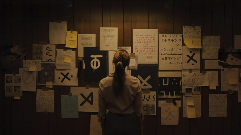 Agent Harker looking at a wall of papers with symbols on them in Longlegs