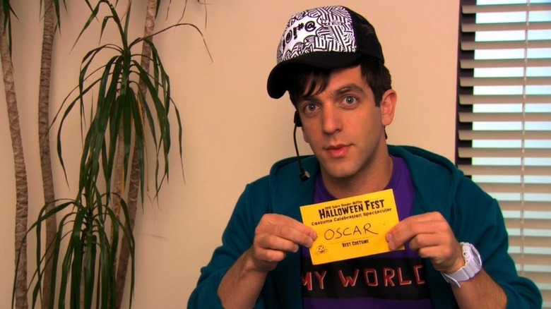 Ryan holding up a Halloween Fest card on The Office