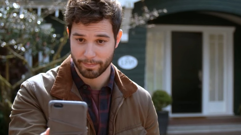 Skylar Astin's Todd looks at his phone while standing outside in So Help Me Todd