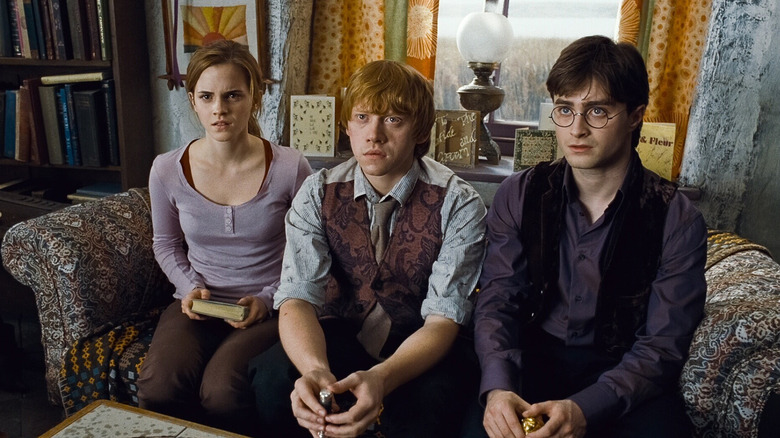 Hermione Ron and Harry sitting on a couch at the Burrow looking shocked in Harry Potter and the Deathly Hallows - Part 1