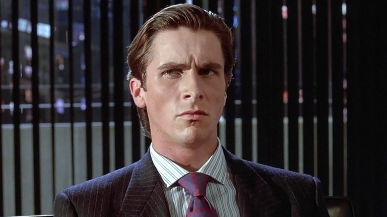 Christian Bale as Patrick Bateman sitting at the board room table in American Psycho