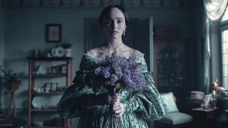 Ellen Hutter holding a bouquet of purple flowers in Nosferatu (2024)