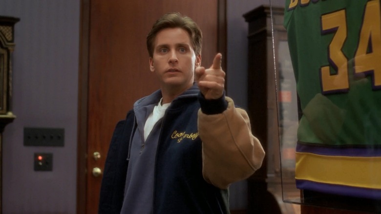 Emilio Estevez as Gordon Bombay in a letterman jacket, pointing at some players, in The Mighty Ducks