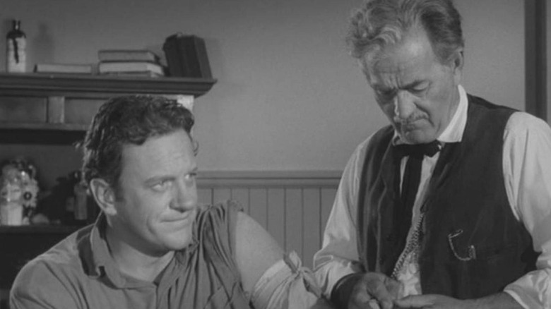 Milburn Stone as Doc Adams gives James Arness as U.S. Marshal Matt Dillon a shot of good manners in Gunsmoke