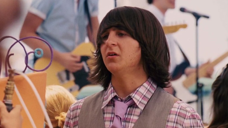 A close-up of Oliver looking concerned with musicians playing in the background in Hannah Montana: The Movie