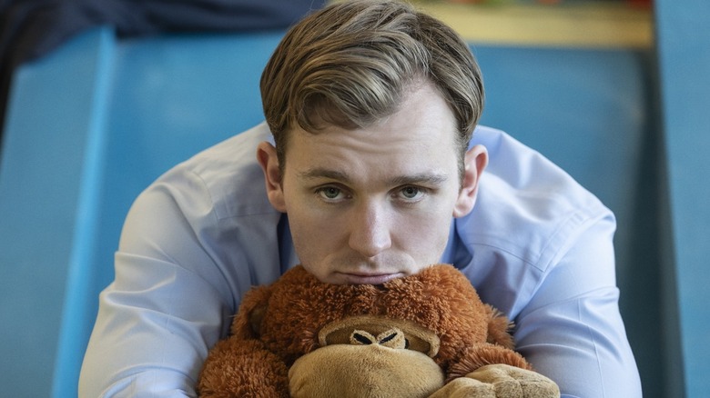 Robert looking sad and resting his head on a stuffed monkey on Industry